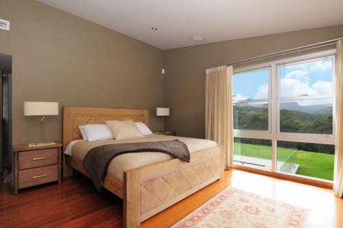 a bedroom with a bed and a large window at Bottlebrush Lodge Great views and a pool in Upper Kangaroo River