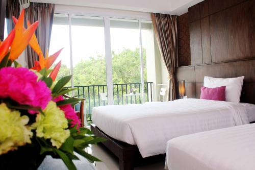 a hotel room with two beds and flowers in front of a window at Lub Sbuy House Hotel - SHA in Phuket Town