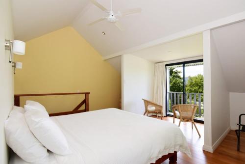 a bedroom with a white bed and a balcony at Cloudsong Chalet 1 Close to the village centre in Kangaroo Valley