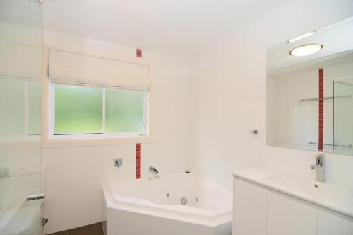 a white bathroom with a sink and a tub at Nellsville Cottage Kangaroo Valley in Upper Kangaroo River