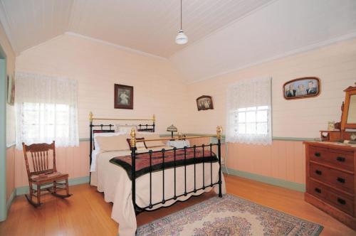 a bedroom with a bed and a chair at The Settlers Cottage Kangaroo Valley in Barrengarry