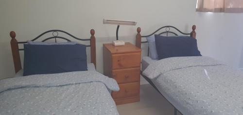 two beds in a bedroom with blue pillows and a night stand at Beatrice in Perth
