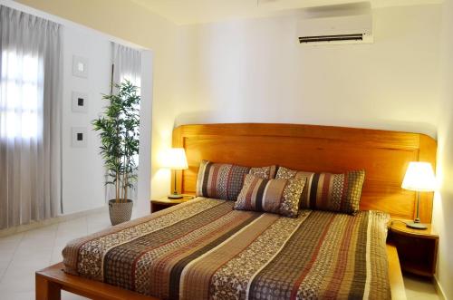 プンタ・カナにあるBeach Villas & Apartments Larimarのベッドルーム1室(ベッド1台、木製ヘッドボード、ランプ2つ付)
