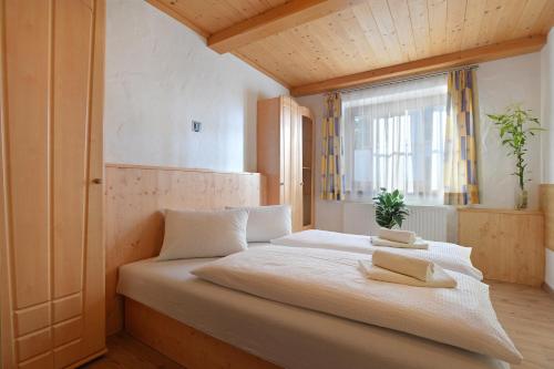 a bedroom with a large white bed with a window at Landhaus Aschaber in Westendorf