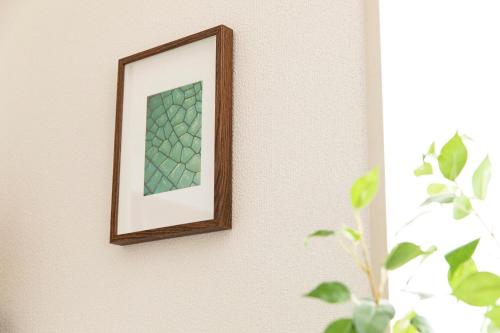 a picture frame hanging on a wall with a plant at RIVER VILLAS HIROSHIMA in Hiroshima