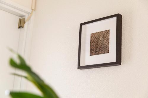 a framed picture on a wall with a plant at RIVER VILLAS HIROSHIMA in Hiroshima