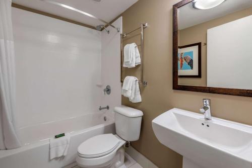 a white toilet sitting next to a bathroom sink at Seafarer Inn & Suites, Ascend Hotel Collection in Jekyll Island