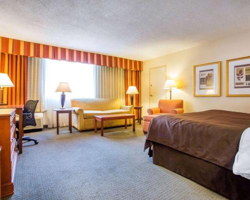 a hotel room with a bed a chair and a desk at Budgetel Inn & Suites Atlanta in Atlanta
