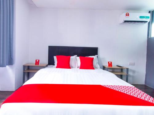 a red and white bed with two red pillows at Intime Hotel Kuchai Lama Kuala Lumpur in Kuala Lumpur