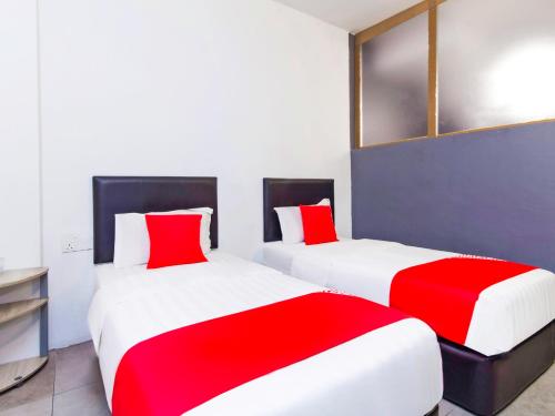 two beds in a room with red and white sheets at Intime Hotel Kuchai Lama Kuala Lumpur in Kuala Lumpur