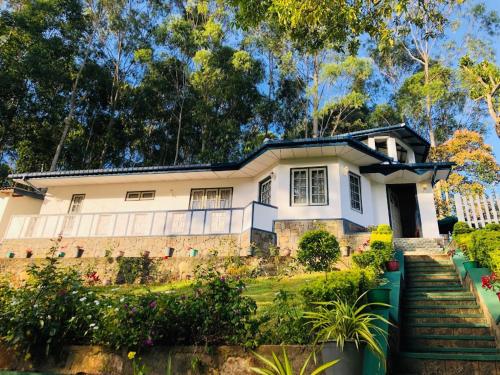 a white house with trees in the background at Windsor Forest bungalow in Bandarawela