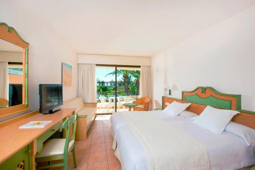 a bedroom with a bed and a desk and a television at Iberostar Waves Playa Gaviotas All Inclusive in Morro del Jable