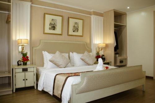 a bedroom with a large white bed with two tables at Golden Prince Hotel & Suites in Cebu City