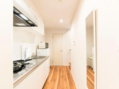 a kitchen with white cabinets and a wooden floor at TRIP POD HIGASHI-HIE in Fukuoka