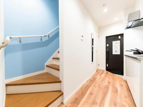a hallway with stairs and a blue wall at TRIP POD HIGASHI-HIE in Fukuoka