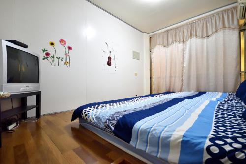 a bedroom with a bed and a flat screen tv at Yiwa Homestay in Taitung City