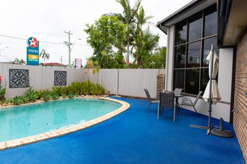 a swimming pool with a table and chairs next to a building at Lantern Motor Inn in Mackay