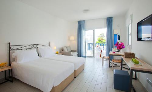a hotel room with a bed and a desk and a television at Aliathon Aegean in Paphos City