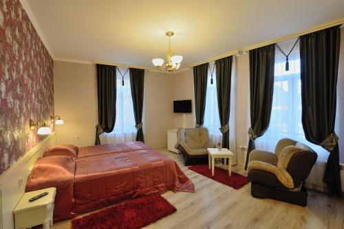 a bedroom with a bed and chairs and windows at Villa Paris in Hisarya