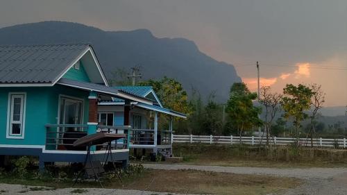 a blue house with a mountain in the background at Ban Thung Talay Mok Chiangdao in Chiang Dao