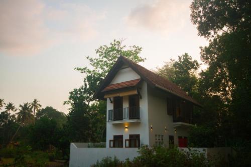 a small white house with a balcony and trees at Villa Mia in Mararikulam