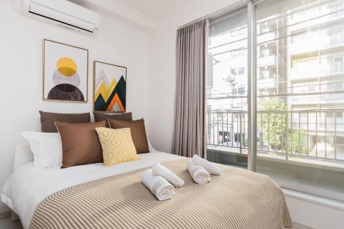 a bedroom with a bed with pillows and a window at Hotel Apartment Ueno Inaricho Sta in Tokyo