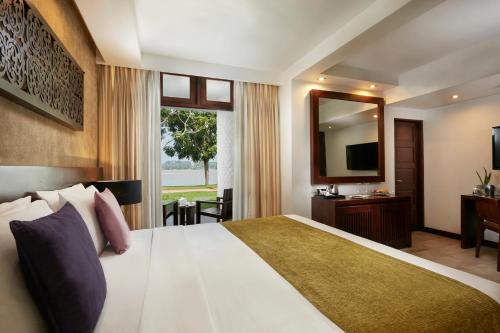a hotel room with a large bed and a mirror at Avani Kalutara Resort in Kalutara