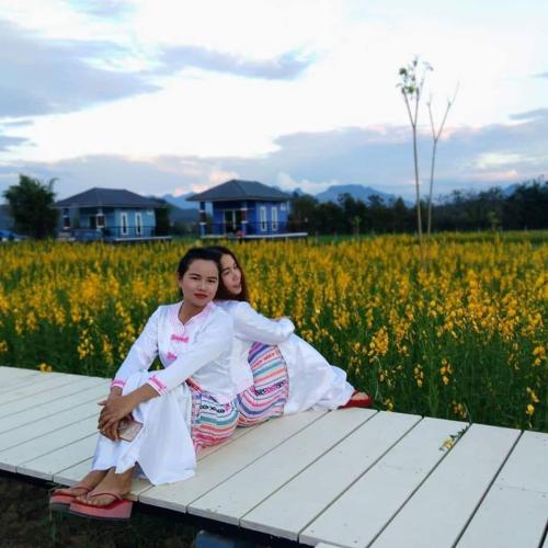 two young girls sitting on a picnic table in a field at Ban Thung Talay Mok Chiangdao in Chiang Dao
