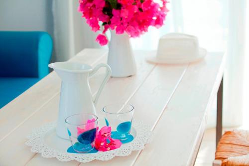 a table with two glasses and a vase and flowers at Aliathon Aegean in Paphos City