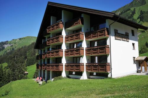 ein großes Gebäude mit Holzbalkonen auf einem Hügel in der Unterkunft Appartment Schröcken in Schröcken