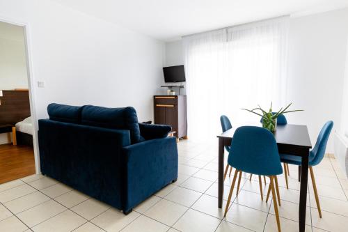 a living room with a blue couch and a table and chairs at Cerise Nantes Atlantis in Saint-Herblain