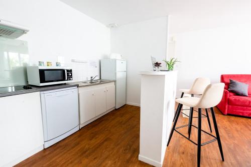 a kitchen with white appliances and a red couch at Cerise Nantes Atlantis in Saint-Herblain