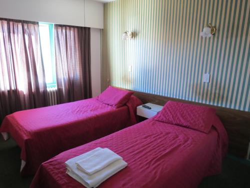 2 camas en una habitación de hotel con sábanas rosas en Hotel Oviedo en Río Gallegos