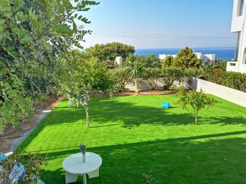a small garden with a green lawn with a white table at Dimitra Hotel in Hersonissos