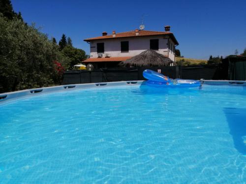 uma grande piscina azul com uma casa ao fundo em Podere San Pierino em Montelupo Fiorentino