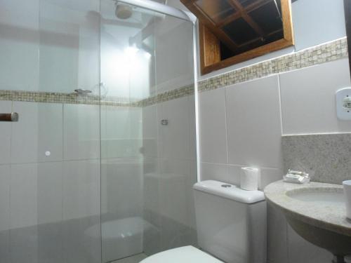 a bathroom with a shower and a toilet and a sink at Suítes e Flats das Papoulas Ferradura In Búzios in Búzios