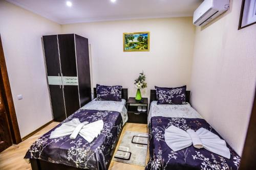two beds in a room with purple sheets and bows at Hotel S.R in Tbilisi City