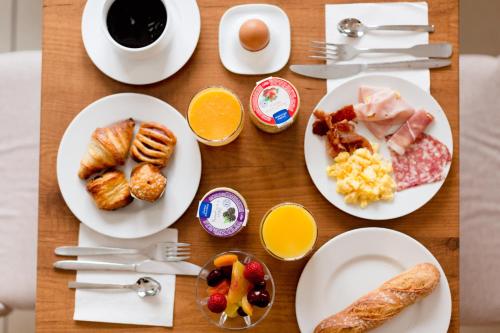 a wooden table topped with plates of breakfast food at Cerise Nantes Atlantis in Saint-Herblain