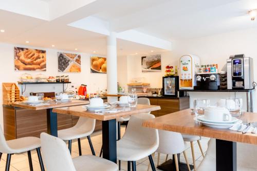 a restaurant with wooden tables and white chairs at Cerise Nantes Atlantis in Saint-Herblain
