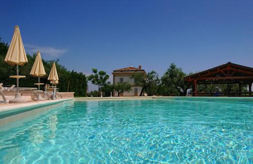 a large swimming pool with chairs and umbrellas at Il Casino di Remartello in Loreto Aprutino