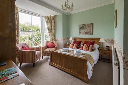 um quarto com uma cama, uma cadeira e uma janela em Cliftons Guest House em Truro