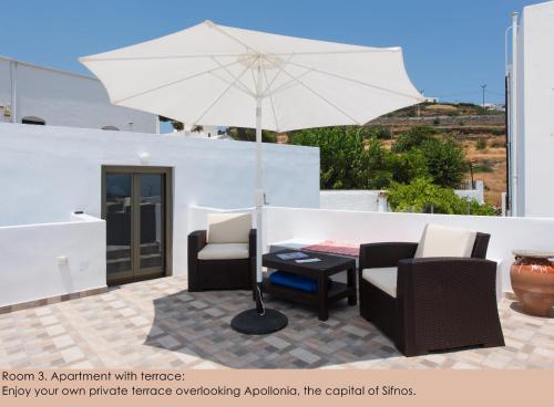 a patio with a table and chairs and an umbrella at Pension Afroditi in Apollonia