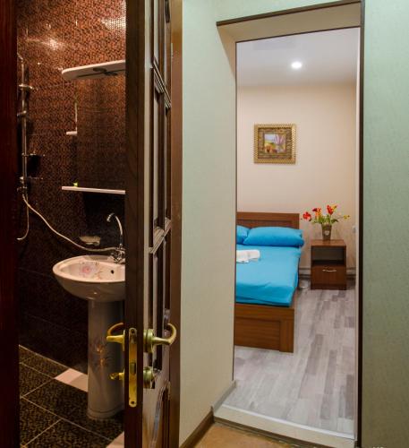 a bathroom with a sink and a bedroom with a bed at Hotel S.R in Tbilisi City