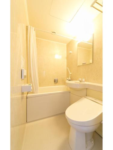 a bathroom with a toilet and a tub and a sink at Hyper-inn Takamatsu Ekimae in Takamatsu