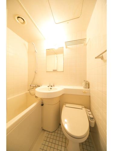 a bathroom with a toilet and a sink and a tub at Hyper-inn Takamatsu Ekimae in Takamatsu