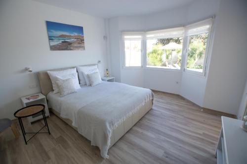 a white bedroom with a bed and two windows at Villa Jandia Modern new apartment Morro Jable Private heated pool big terrace and parking in Morro del Jable