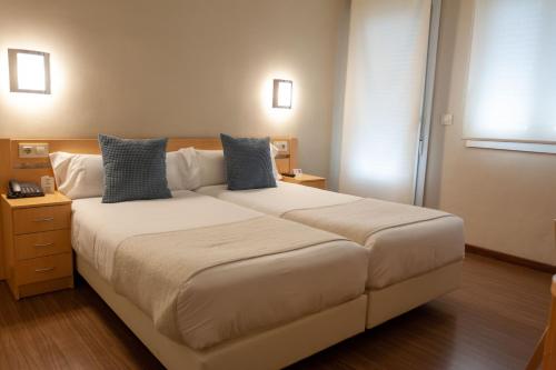 a bedroom with a large white bed with blue pillows at Vettonia Hotel in Merida