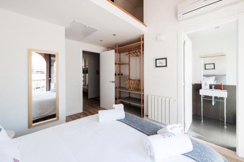 a white bedroom with a large bed and a sink at Petit Luxe Tobella Dreta in Terrassa