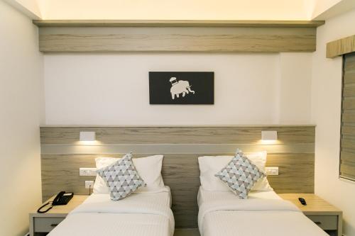 a bedroom with two beds and a picture of a sheep at Sapphire Club Metro in Ernakulam