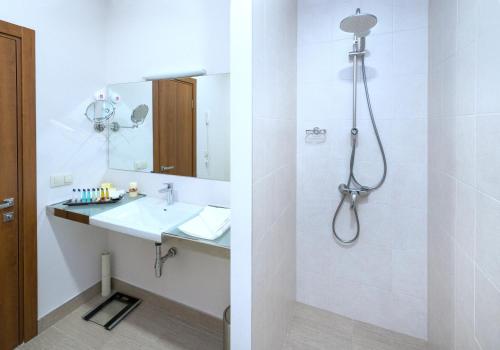 a white bathroom with a shower and a sink at Ani Grand Hotel Yerevan in Yerevan